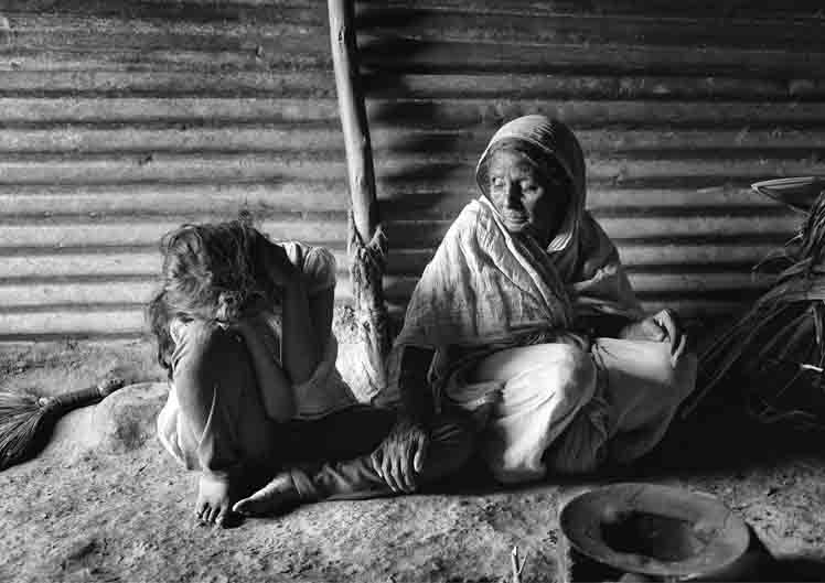 black and white image of two women in a tin shed-caste based violence