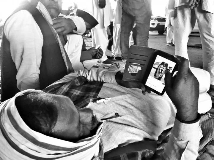 A man lying down with his head covered with a cloth looking into his mobile phone-farmers protest