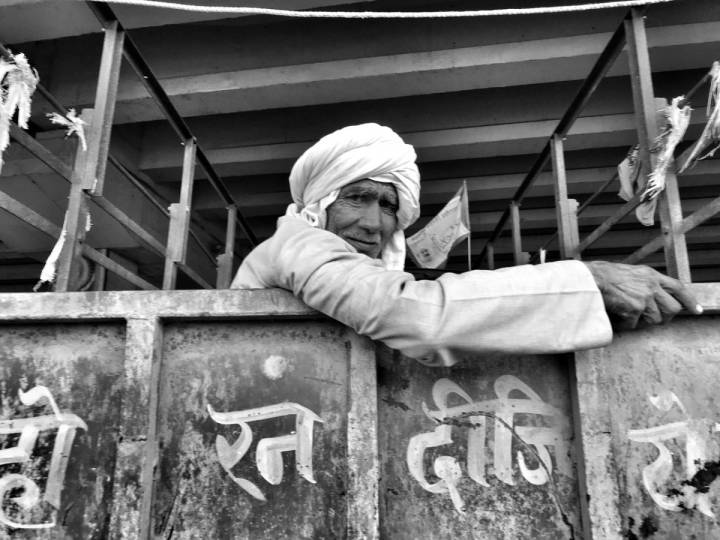 A man wearing a turban sitting inside a truck looking outside into the camera-farmers protest