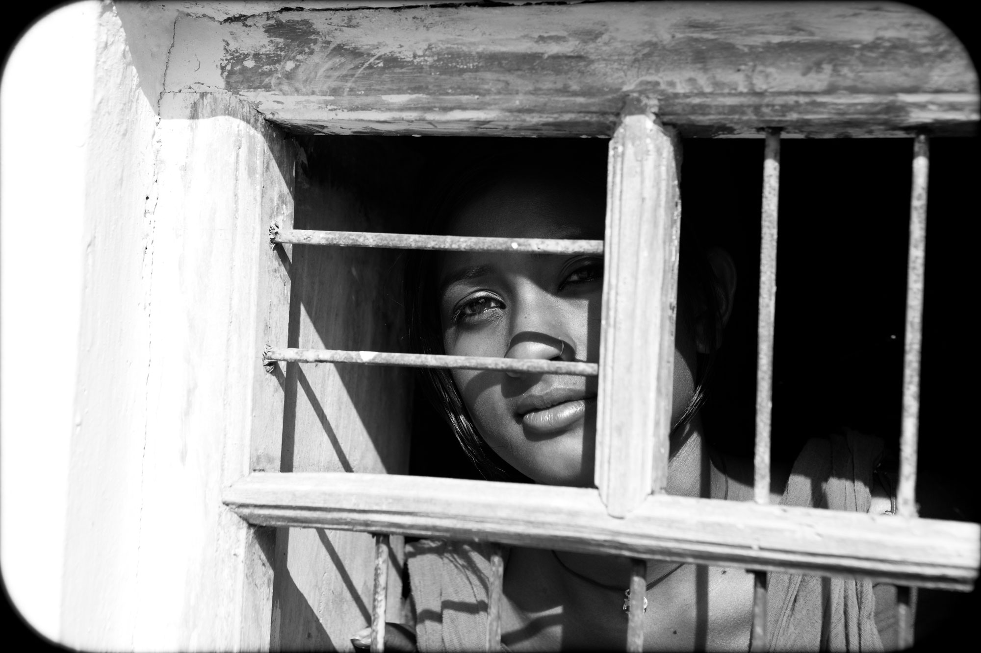 An Indian woman looking out from behind window bars 