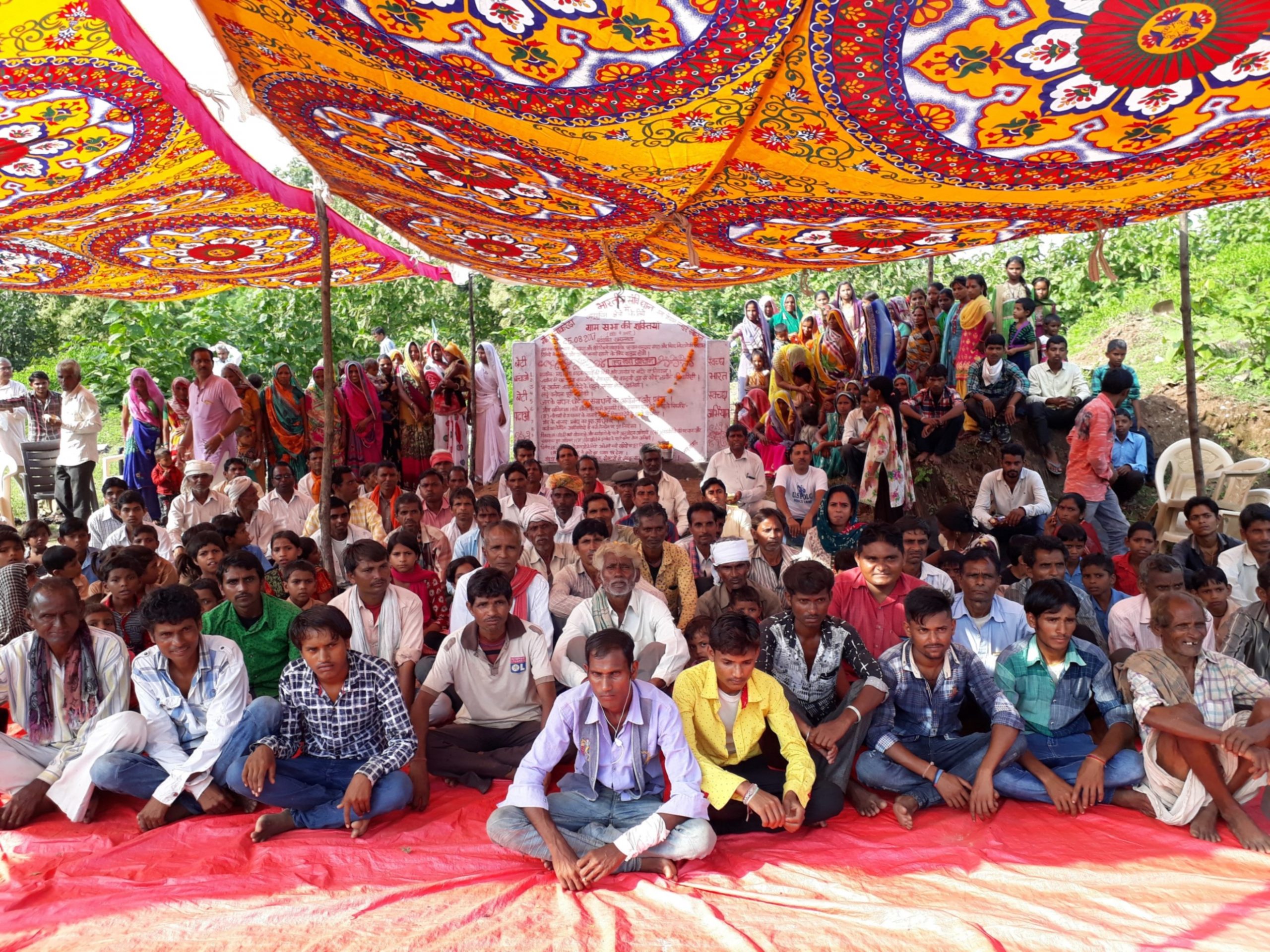 Several villagers sitting under a shade