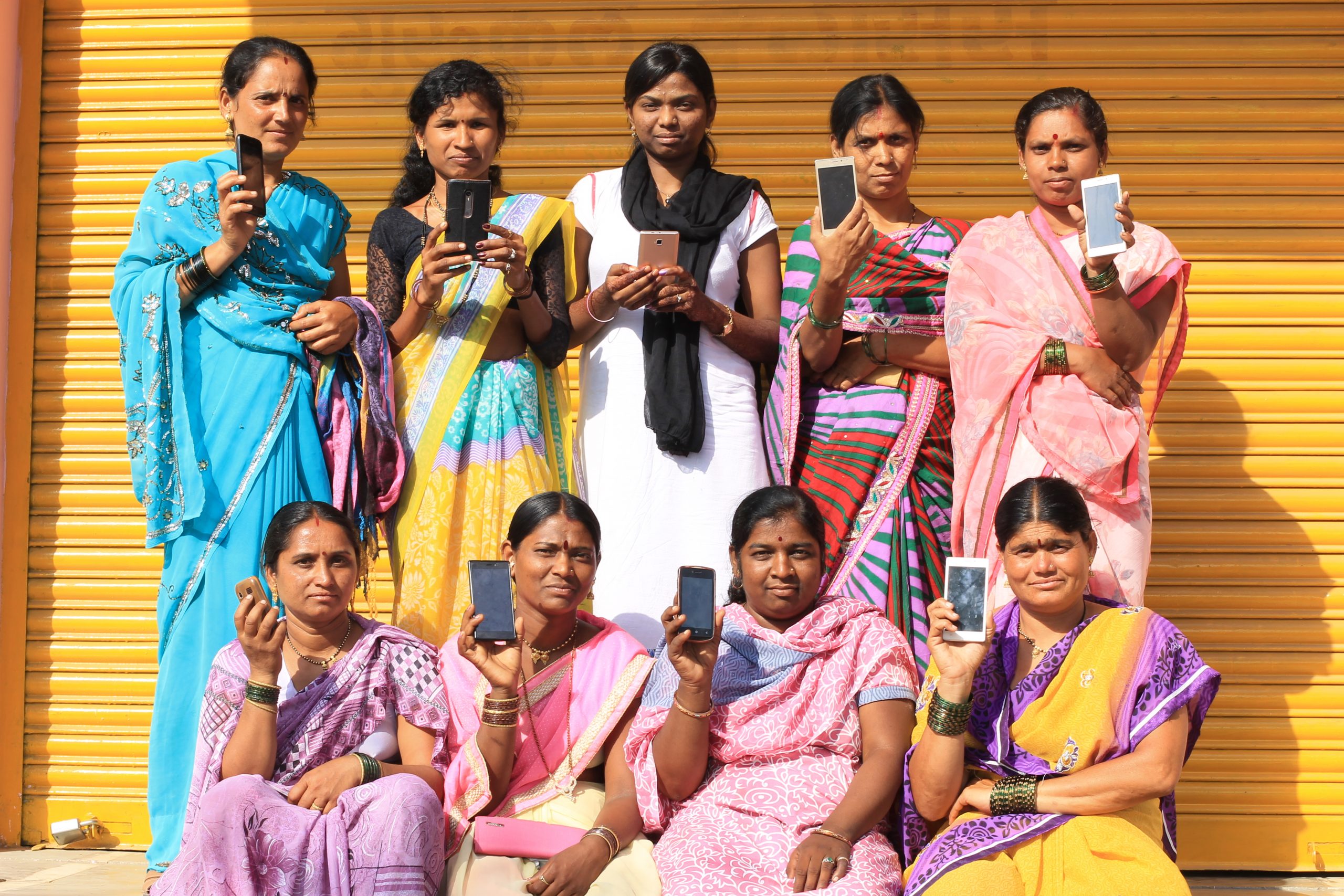 Group of women holding mobile phones_govt schemes_haqdarshak