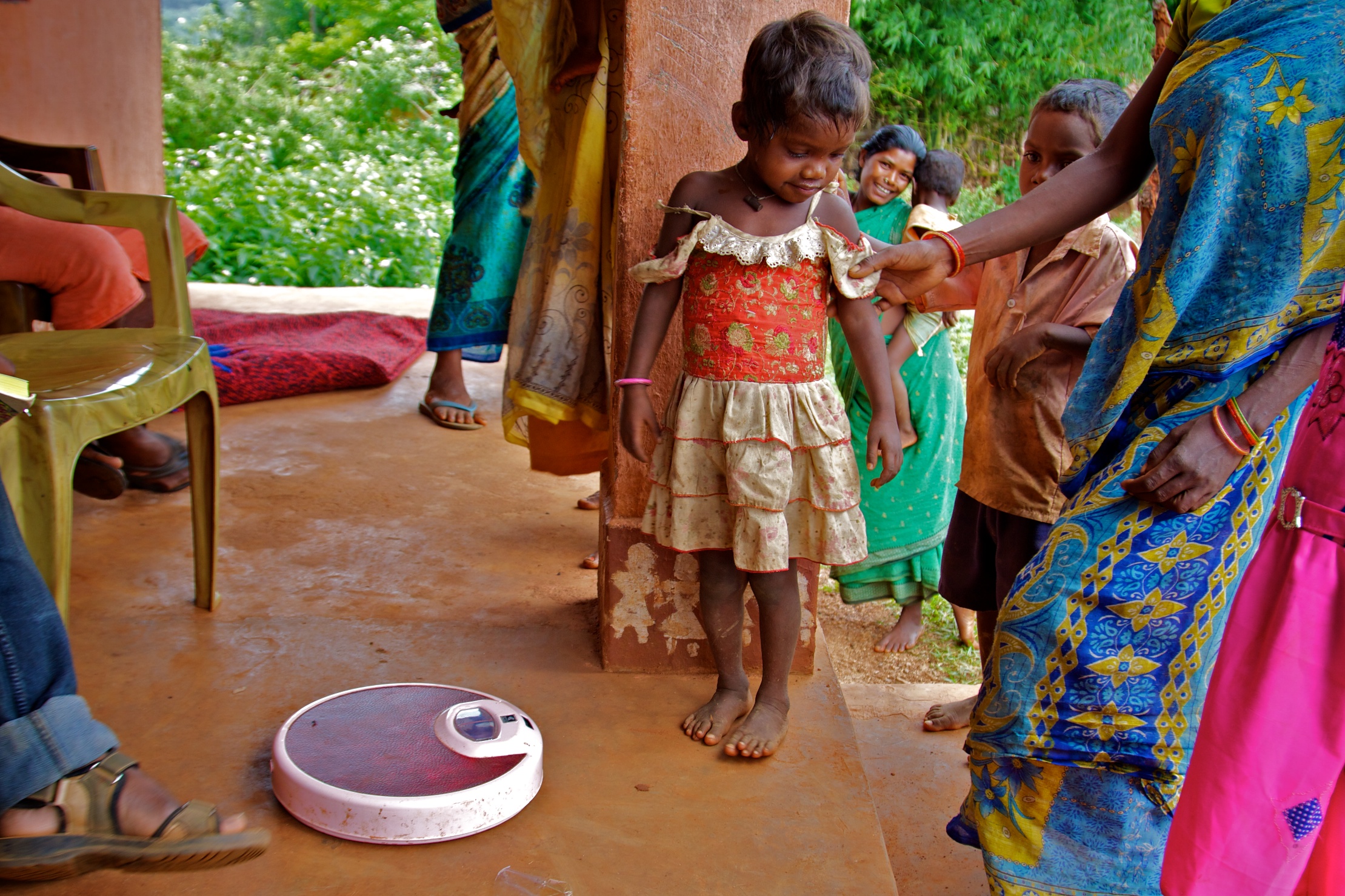 A young Indian girl child standing next to a weighing scale