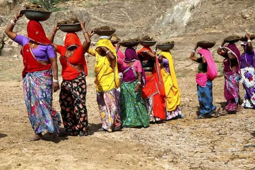 NREGA workers standing in a line behind each other with their faces covered with sarees holding pans on their head-photo credit PTI