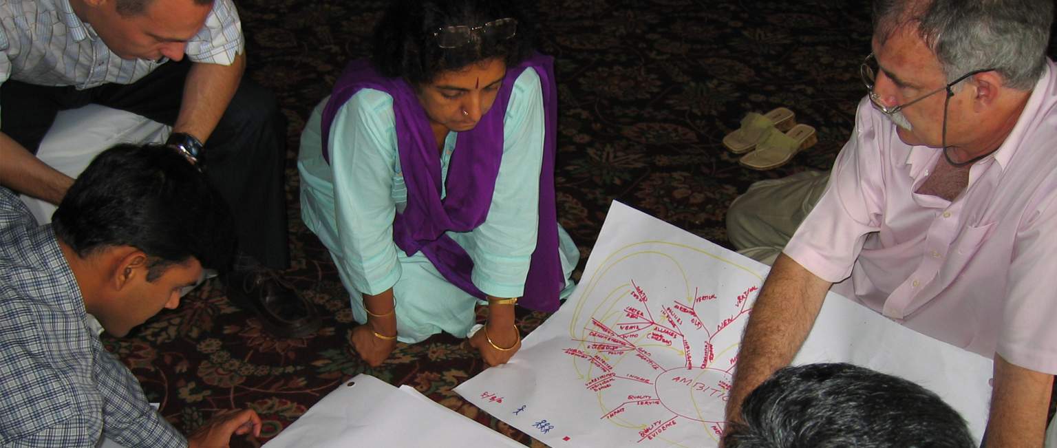 man sitting on the ground with a chart and surrounded by a group of people-social entrepreneurship