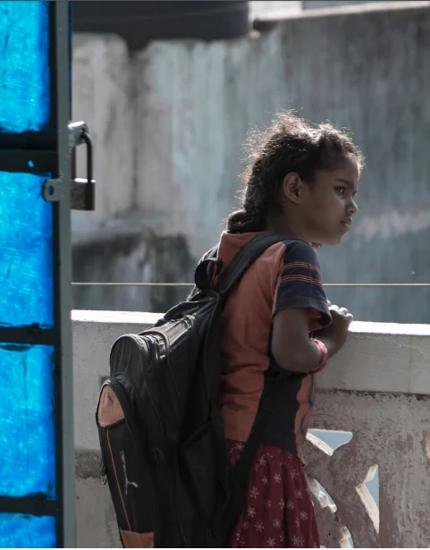 a young girl with a school bag looking out from a terrace
