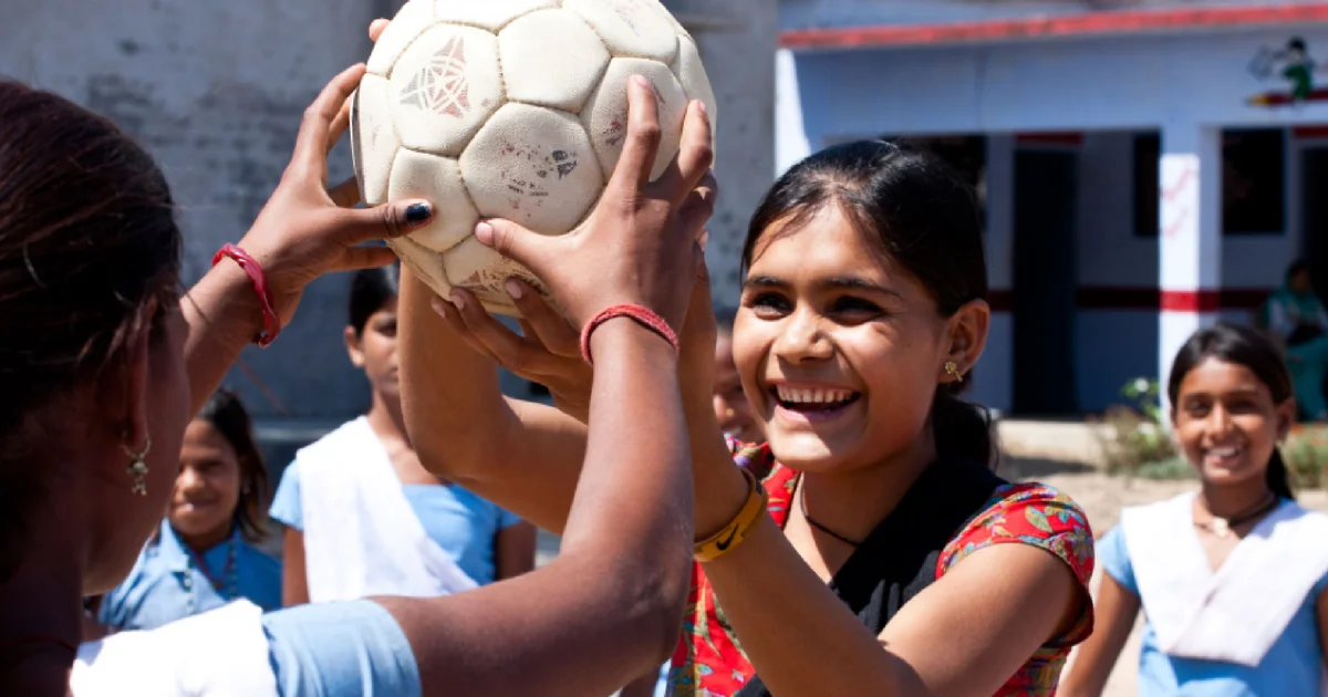 Two girls holding a football in the air