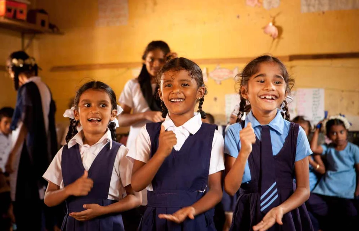 A group of young Indian girls in school uniform playing in a classroom