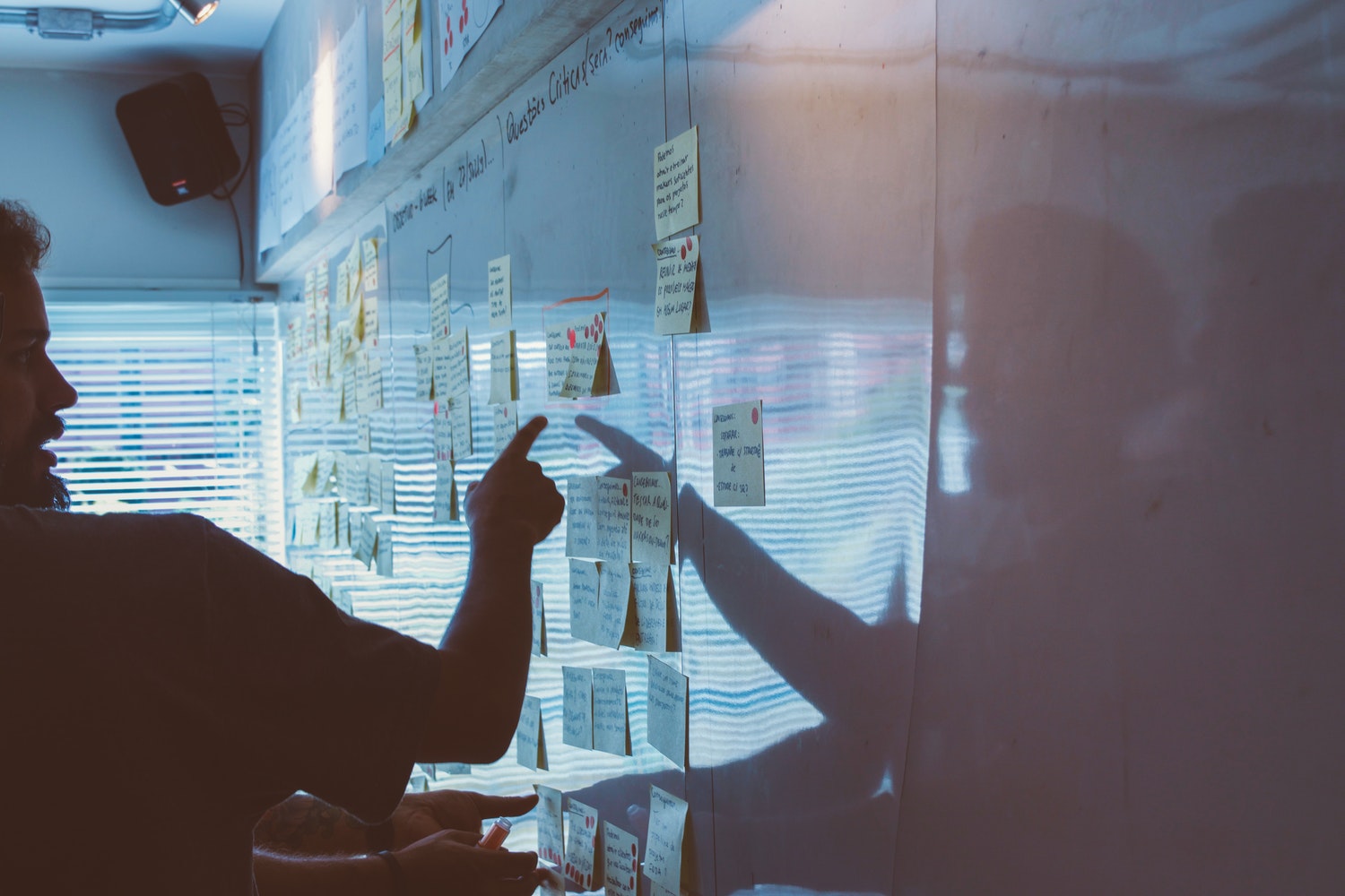 A man pointing at some post its and explaining them