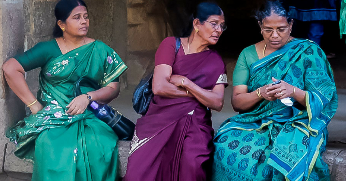 3 women In sarees looking at a phone