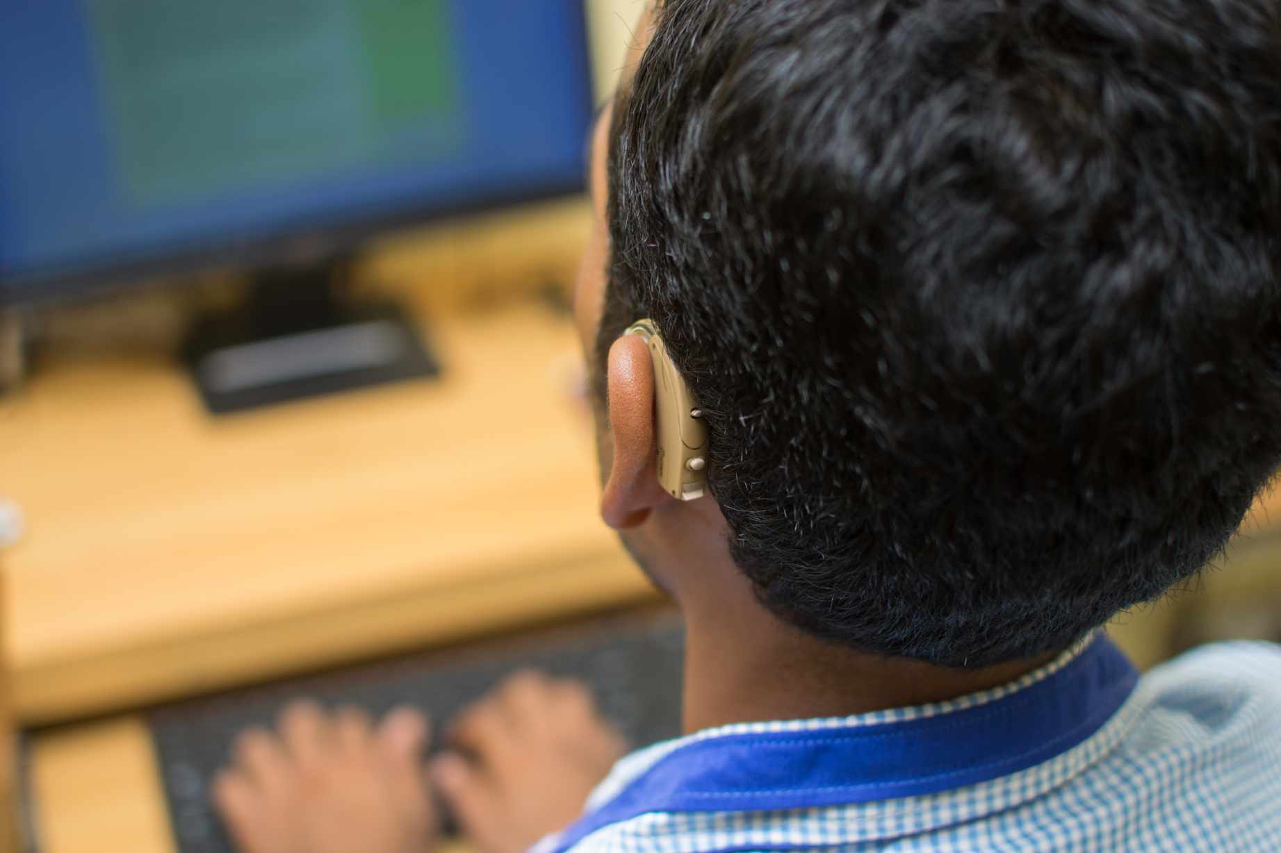 young boy using a computer wearing a hearing aid-disability