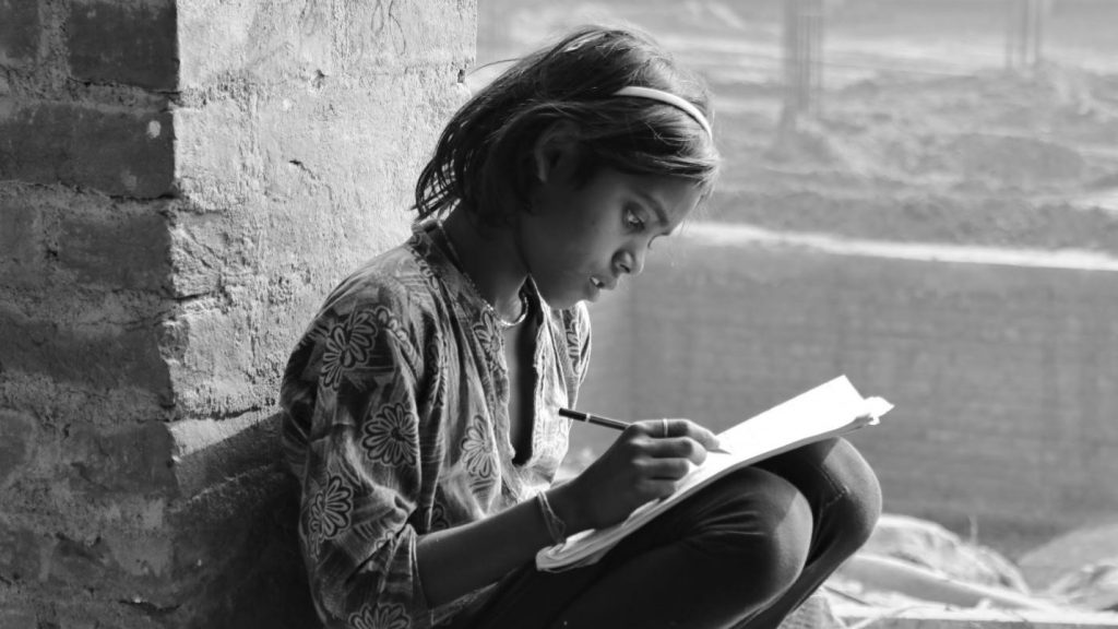 Sharmili, a young migrant girl at the construction site, does her homework