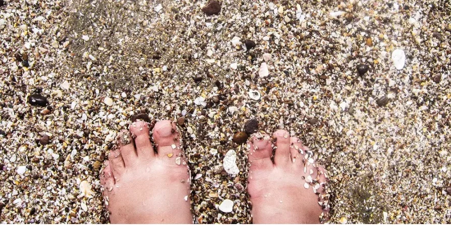Photo by a blind photographer of feet on a beach in the sand