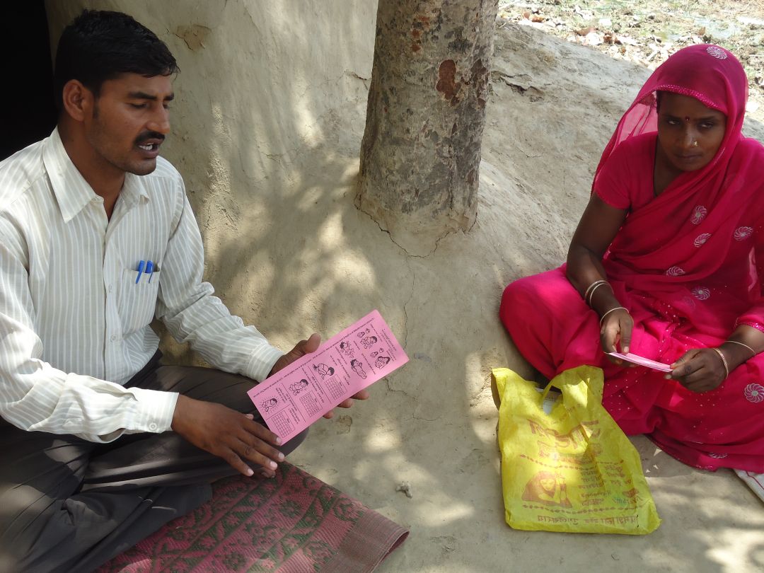 A man and woman sitting next to each other with the man reading out a pamphlet_ Picture courtesy:Yunus Social Business