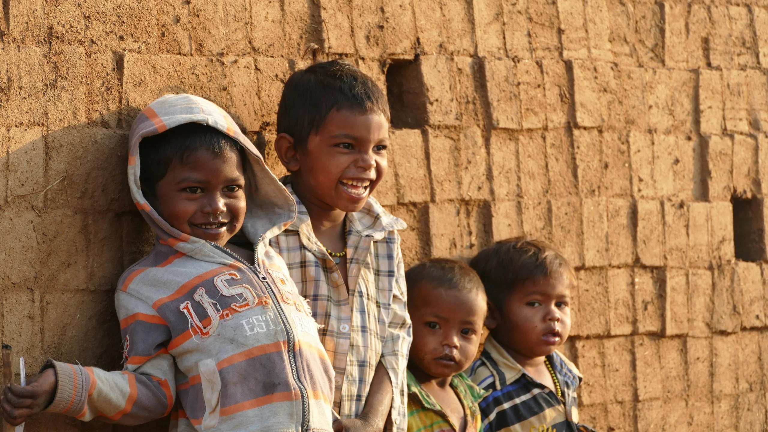 Young children laughing next to a brick kiln in Sonale, India