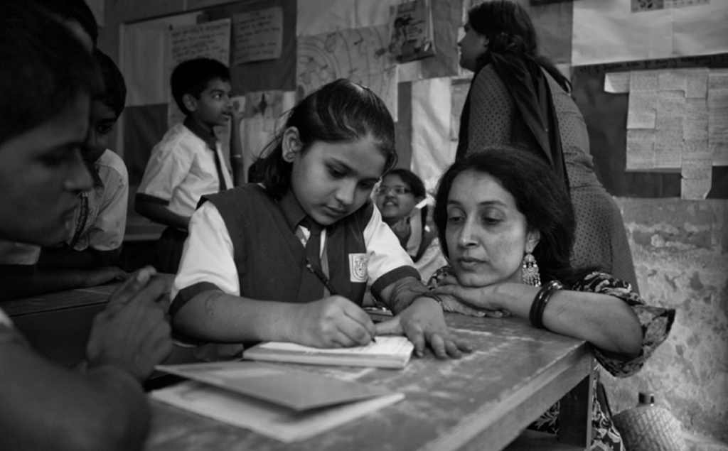 Shaheen Mistri sitting at a desk with a child