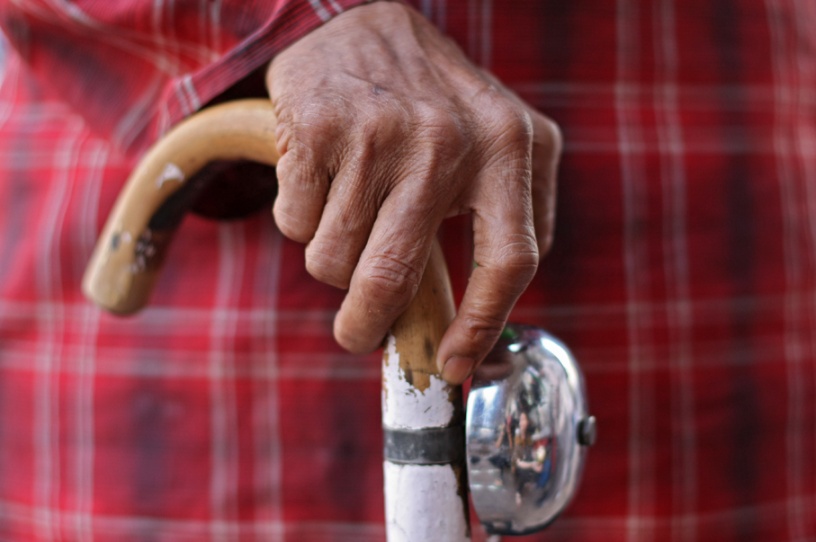 Close-up of a hand supported by a walking cane