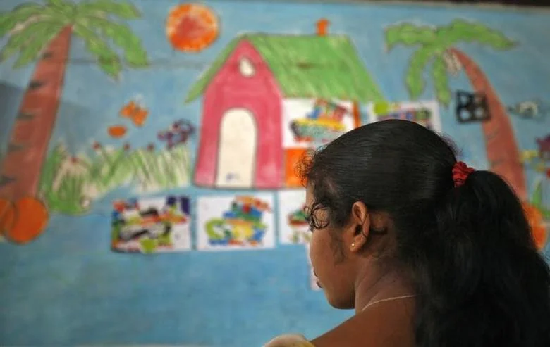 A girl looking at a classroom wall with paintings on it