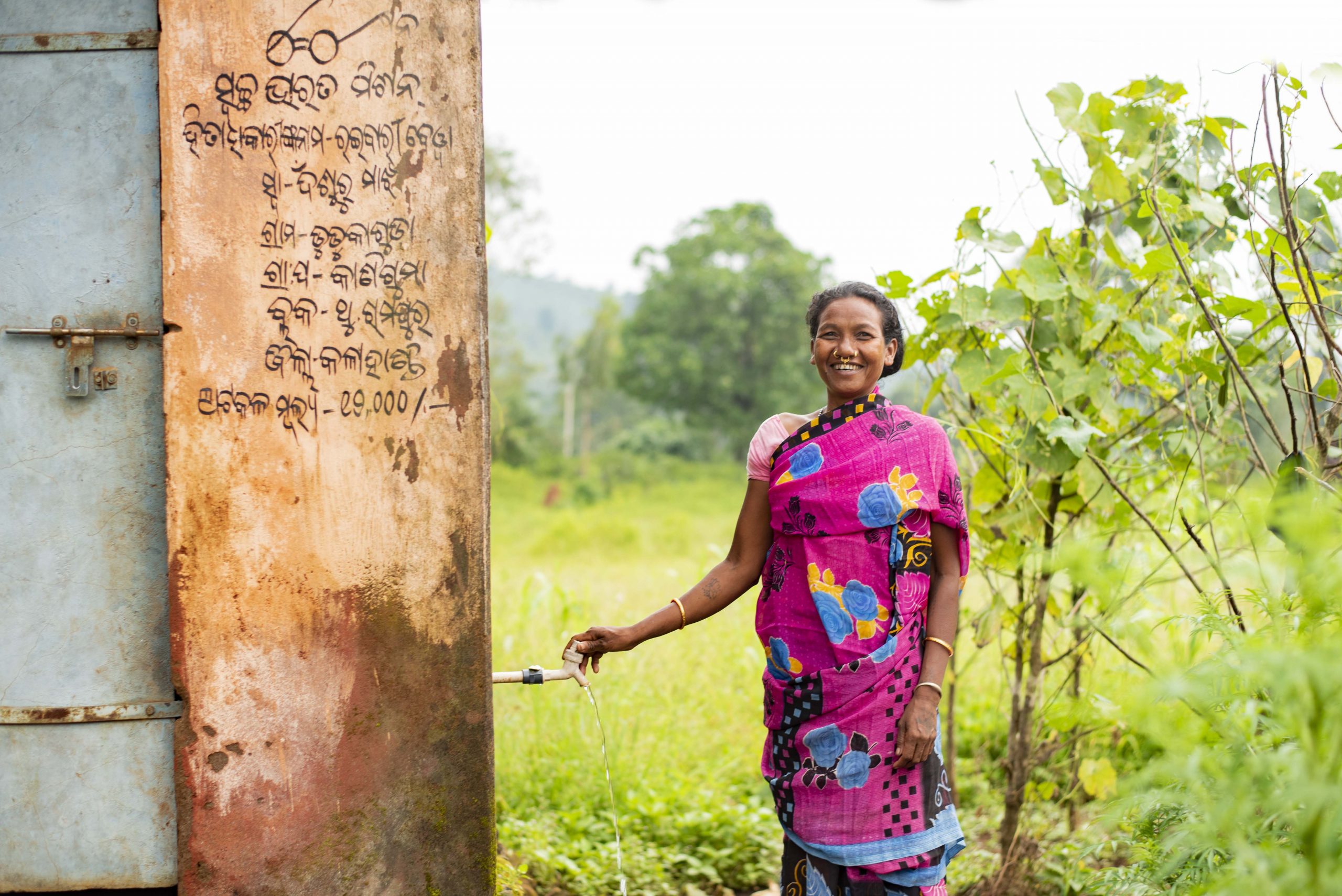 woman in odisha standing next to a toilet_rural sanitation_gram vikas