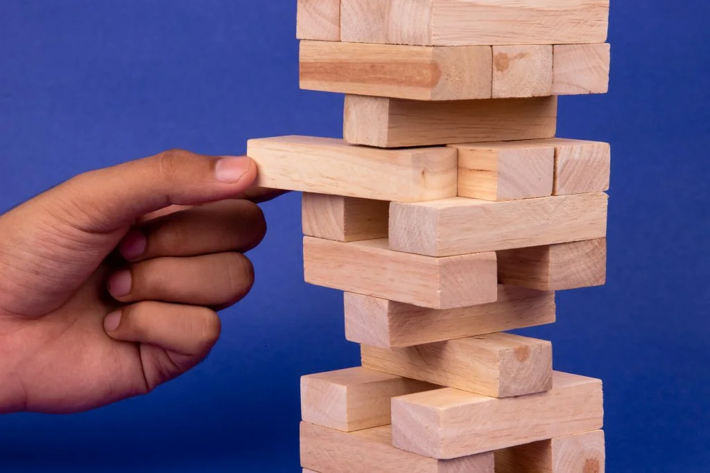 An inclined wooden block tower jenga game with hand-social stock exchange