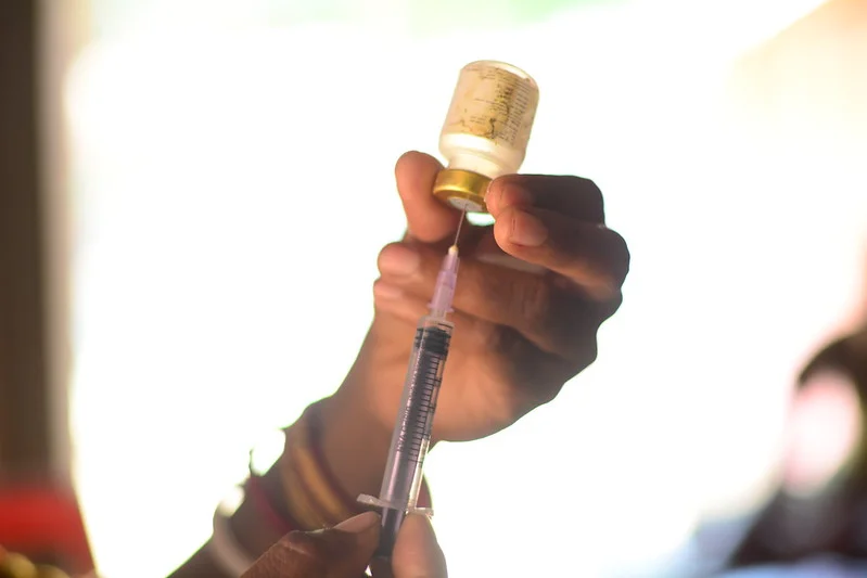 A person holding a vaccine bottle and syringe-picture courtesy-Flickr