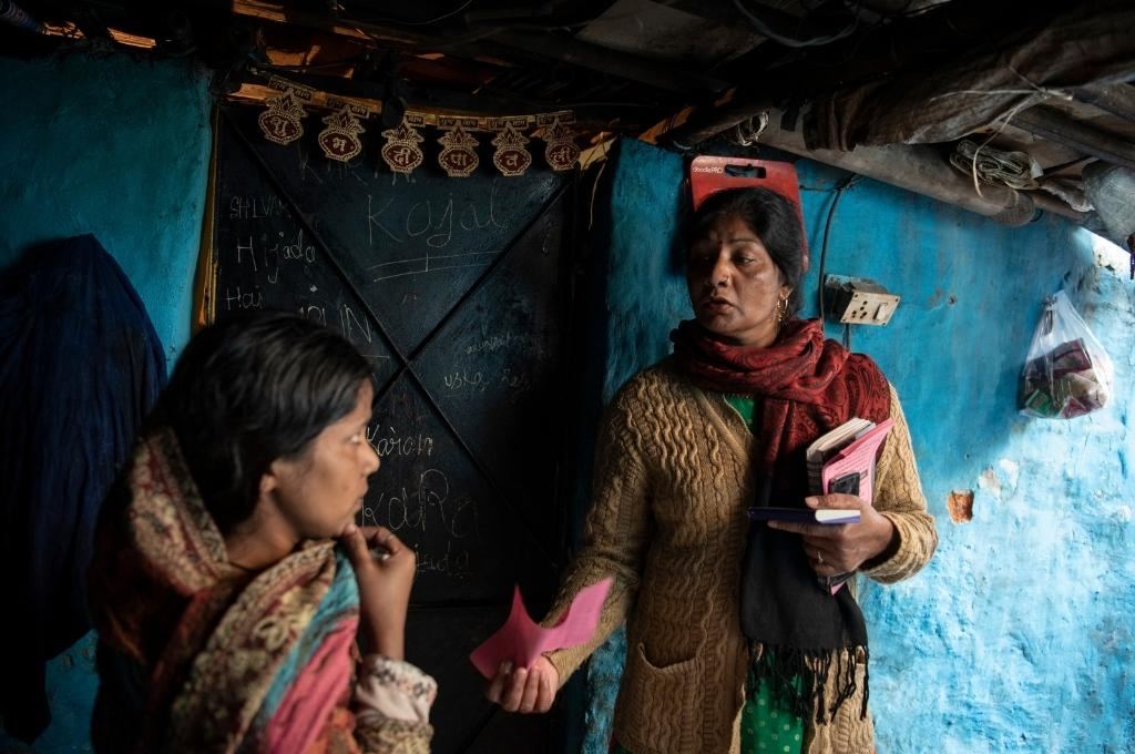 Haqdarshak (someone who shows you your rights; part of the organisation called Haqdarshak) showing a pink slip to a woman-upskilling field workers