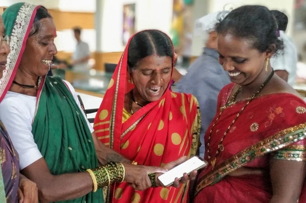 three women looking at a smartphone and smiling-