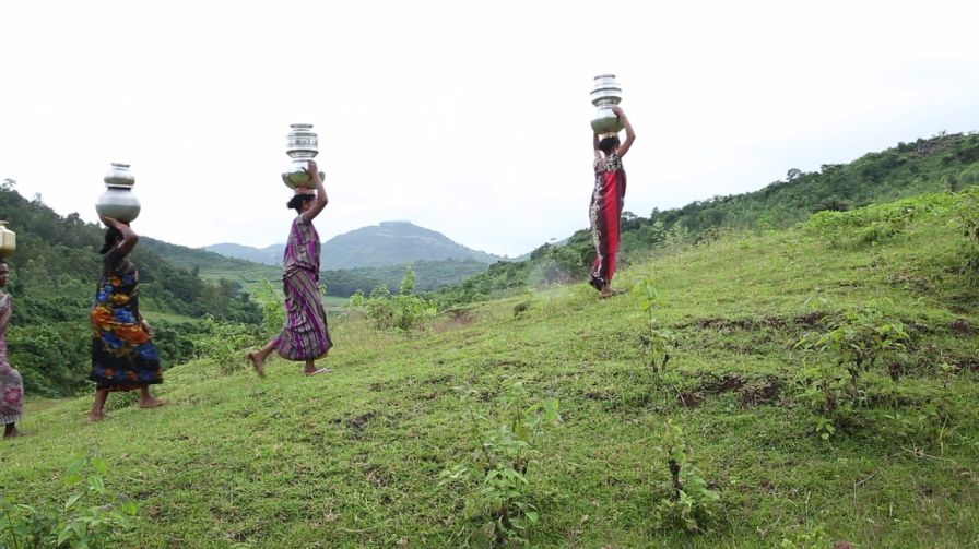 Women walking up a hill with metal pots-water scarcity