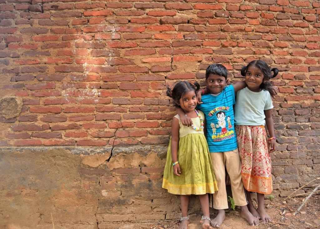 Three smiling kids against a red brick wall. Union Budget 2022 must focus on children