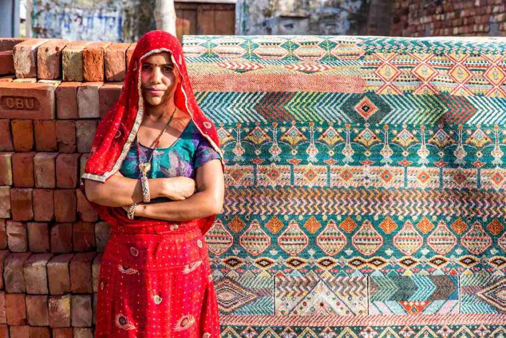 woman artisan standing in front of a rug-artisan economy