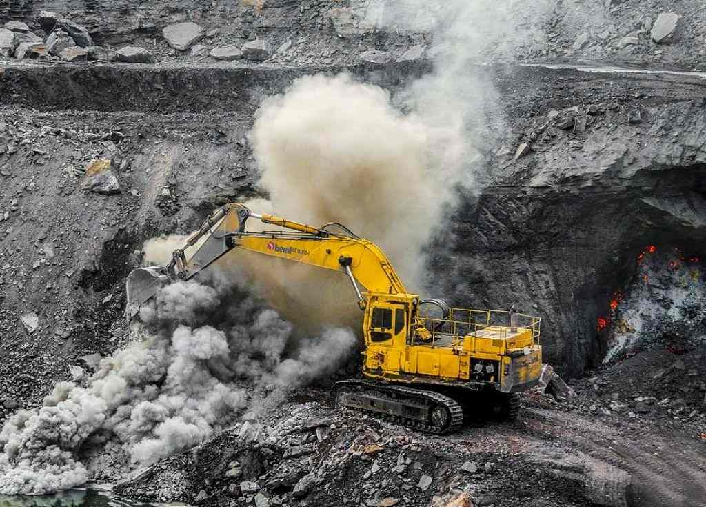 A yellow mining truck at coal site_Wikimedia commons. At COP 26, India pledged to achieve net-zero carbon emissions by 2070. However, its coal expansion plans and lack of investment in renewable energy sources tell a diff