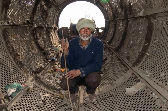 An informal worker picking waste from inside a trommel screen at the Ghazipur landfill near New Delhi-waste management