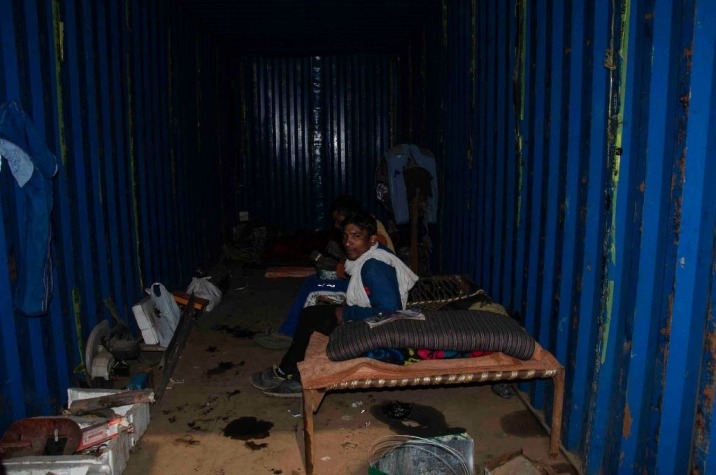 An informal worker at the Ghazipur landfill seated on a bed in on-site container housing-waste management