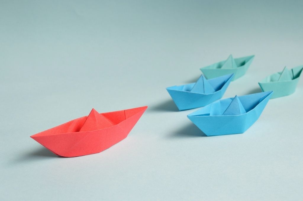 One red paper boats followed by two blue boats and two green boats. A recent report unpacks the challenges around people management in the social sector, and what can be done about them | Pexels