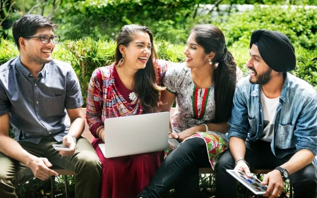 Young people sitting around a girl who is sitting with her laptop-youth