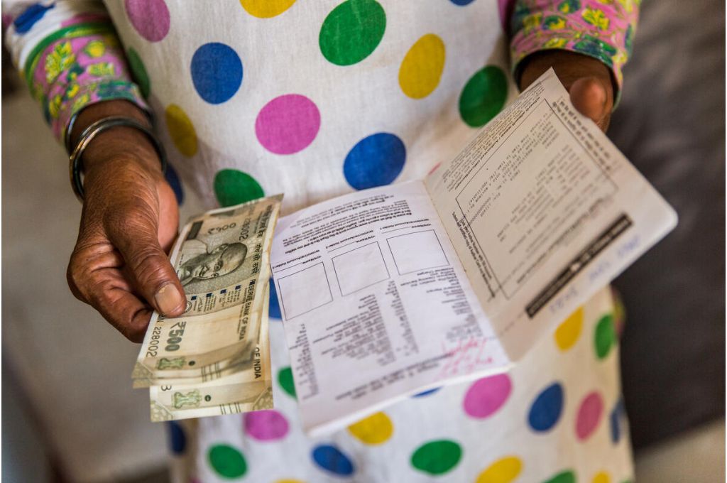 woman with cash and a passbook in hand - universal basic income