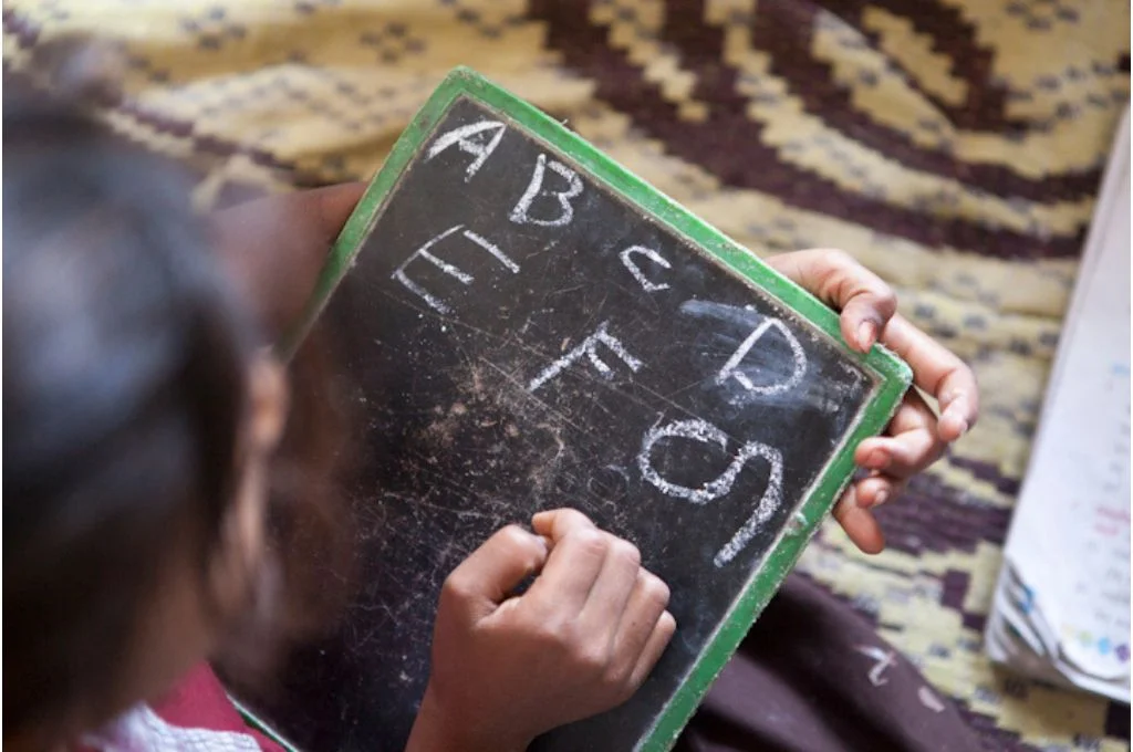child writing on a blackboard-education