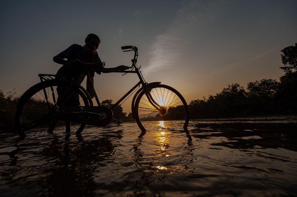 Man takes his bicycle across water _migrant workers