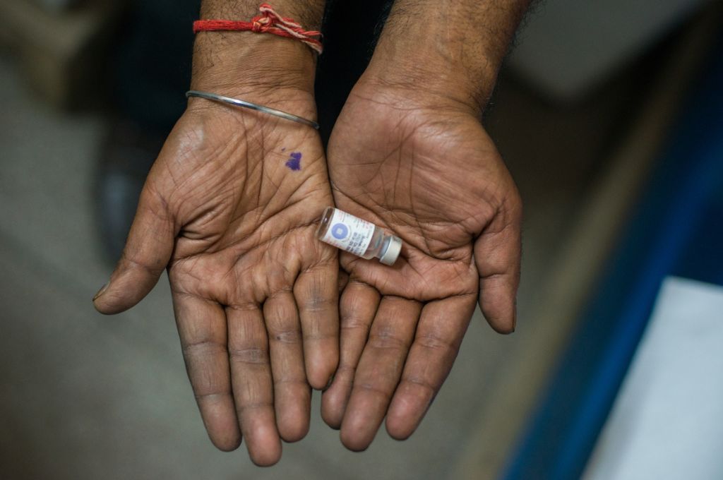 A topshot of two hands holding a vaccine_PM-JAY