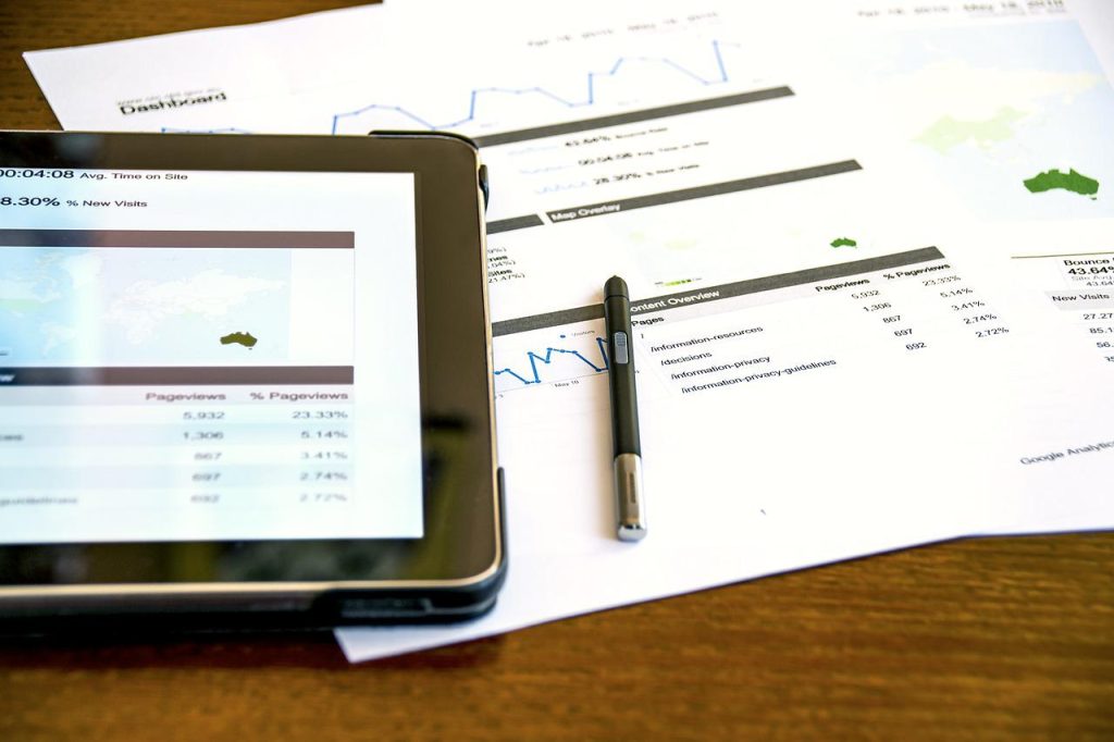 a tablet showing a dashboard, some papers with graphs and a pen - data dashboard