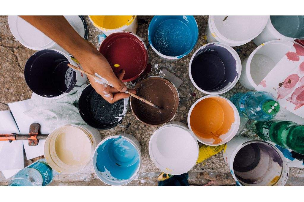 aerial shot of hand holding painbrush over paint cans-impact investment