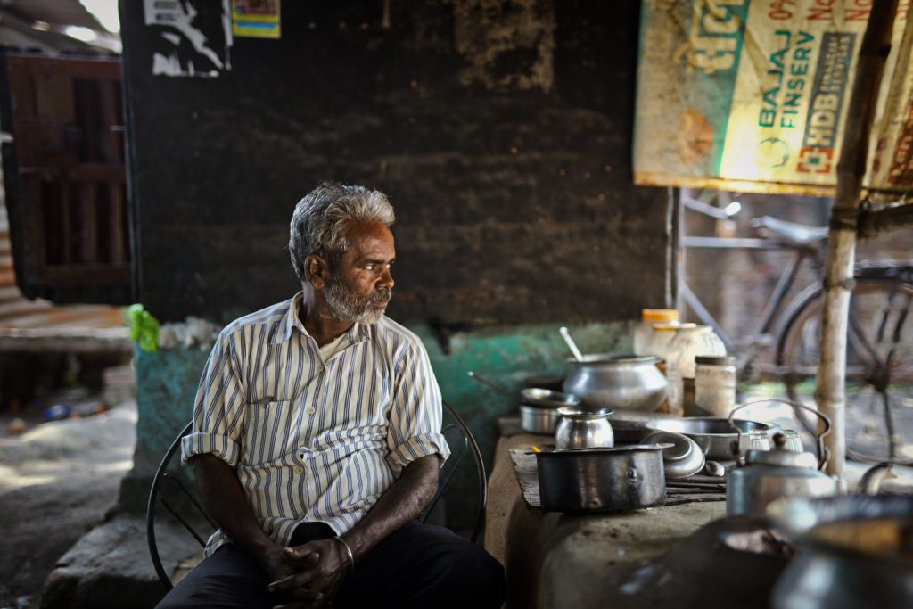 A photo of a man who runs a tea-stall, sitting next to some untensils-coal mining 
