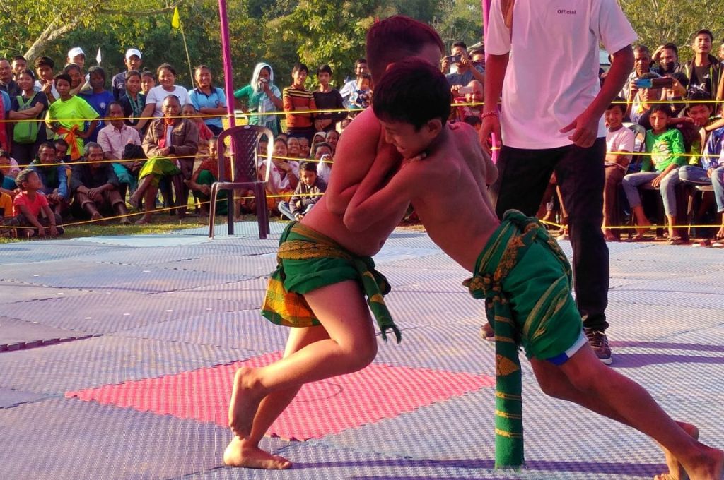 Two young boys wrestling in traditional Bodo attire in front a crowd_Khomlainai