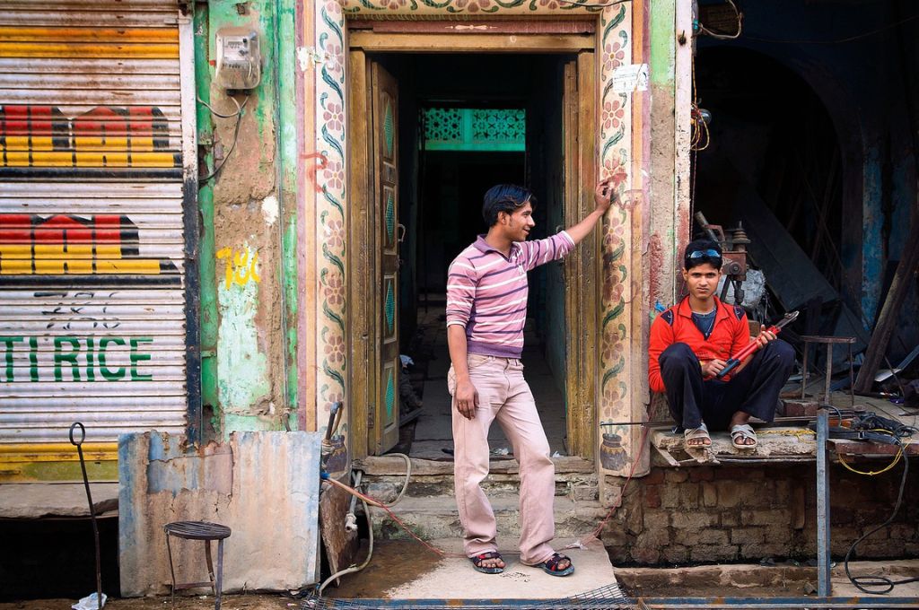 Two men sitting outside a shop in the street-young men and boys