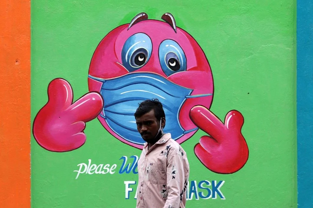 A man walks past a Covid-19 coronavirus awareness mural along the roadside in Chennai-crisis relief