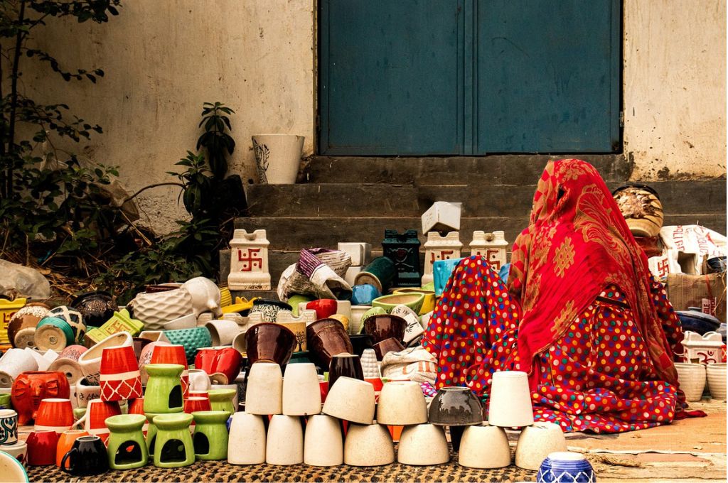 A woman sitting next to various handmade clay cups and mugs-women entrepreneurs
