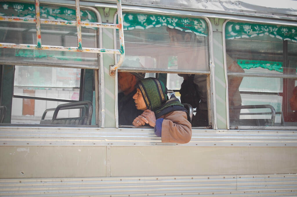 An elderly woman sitting in a bus.