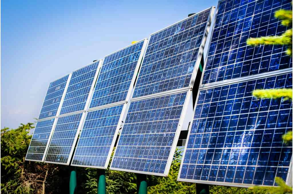 The image shows ten solar panels placed in five rows. The image has been taken during the day time and there are trees in the background._Solar plant