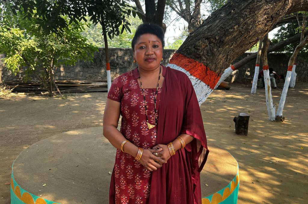 A woman in a red dress standing in front of a tree--tribal women