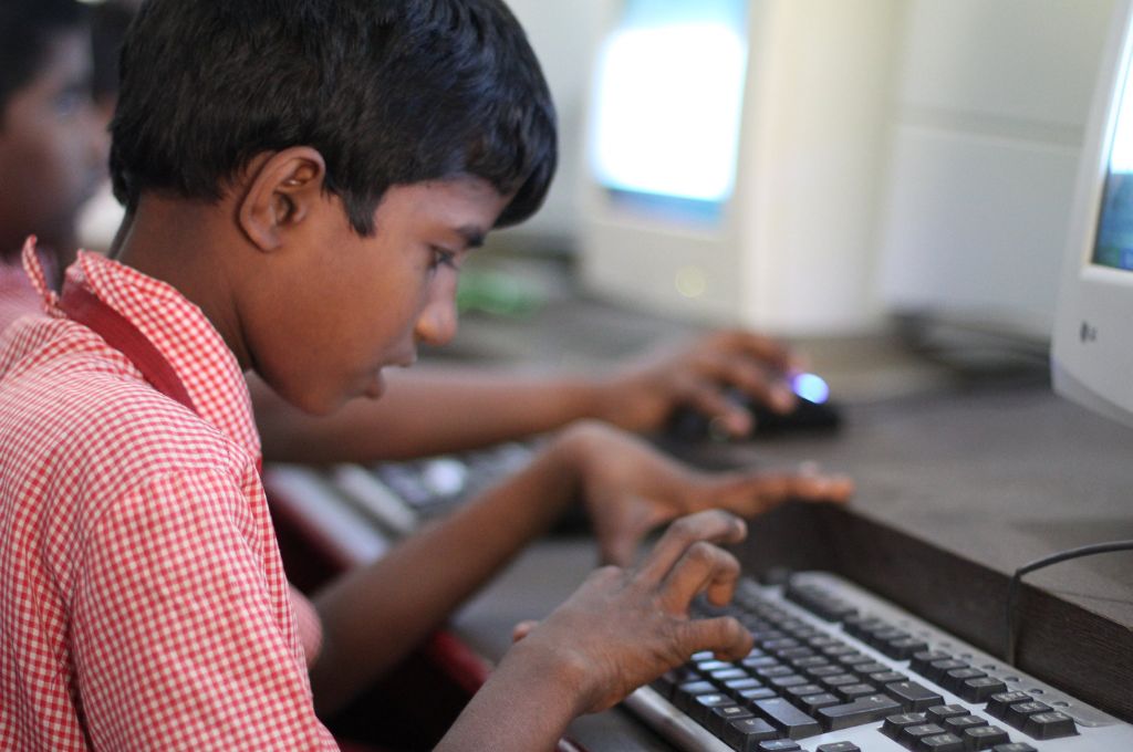 A boy in school uniform typing on computer keyboard_union budget education